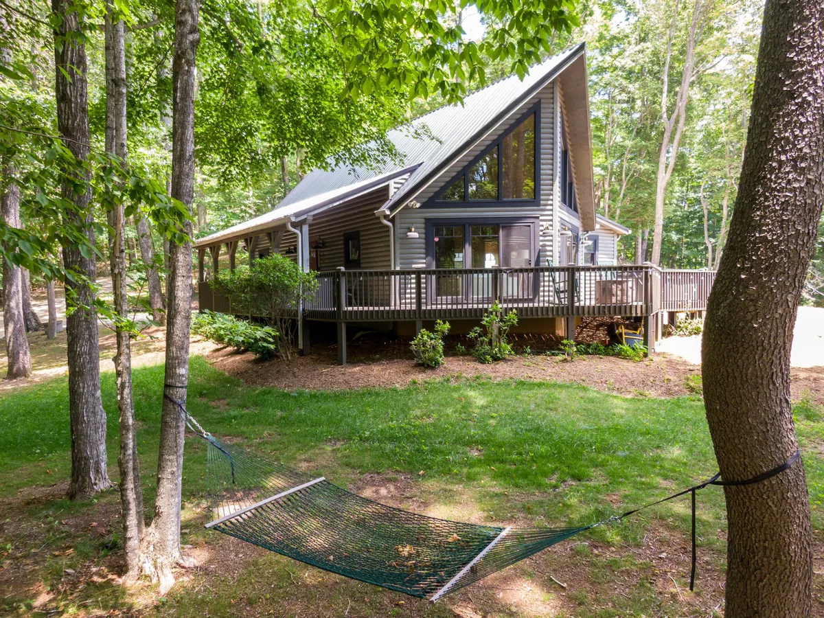 A peaceful outdoor setting featuring a hammock under the shade of trees, the cabin visible in the background. The scene captures relaxation amidst nature, with space for family activities and the potential to spot local wildlife.