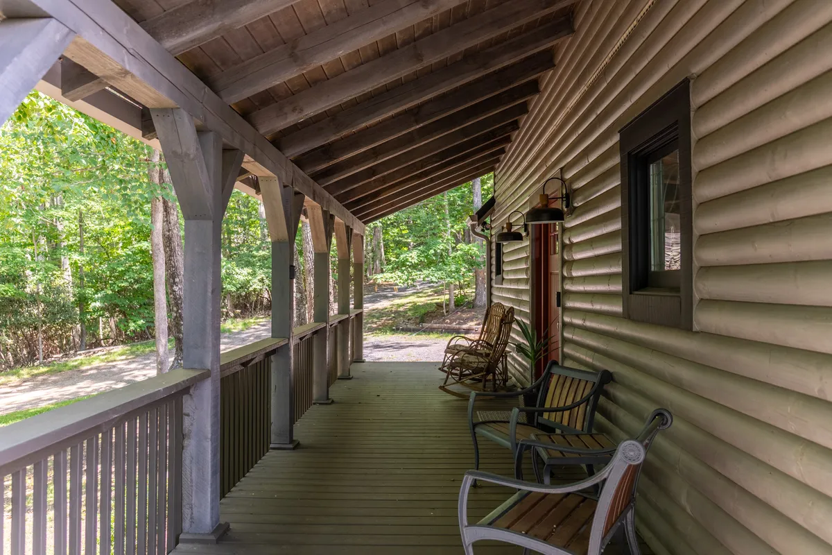A covered porch lined with wooden rocking chairs, overlooking lush natural surroundings. The setting evokes moments of relaxation, storytelling, and quality family time after a day of adventure.